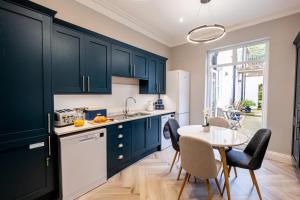 a kitchen with blue cabinets and a table with chairs at St Kitts Apartment in Filey