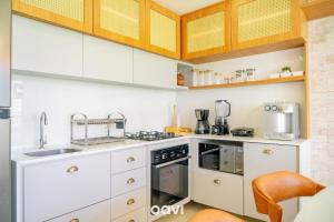 a kitchen with white appliances and wooden cabinets at Qavi - Flat Vista Mar de Pirangi #Living14 in Pirangi do Norte