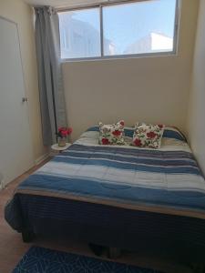a bed with two pillows in a room with a window at Departamento Avenida Peru in Viña del Mar