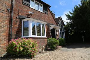 a brick house with a window and some flowers at Debden Guest House in Hillingdon