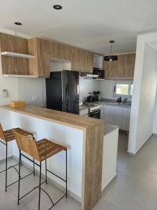 a kitchen with a counter with two chairs and a refrigerator at Beautiful brand new apartment in Neuquén +6 photos