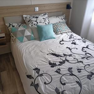 a bed with a black and white comforter and pillows at Jolie mobilhome 331 in Gastes +34 photos