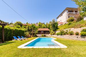 a swimming pool in a yard with chairs and a house at Bungalow Chalé da Caniçada in Rio Caldo
