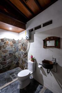 La salle de bains est pourvue de toilettes et d'un mur en pierre. dans l'établissement Vintage room 2 in Joglo House By penggemarlawas, à Kamparganya