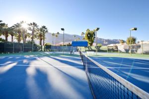 a tennis court with palm trees and a net at The Deauville Gem in Palm Springs