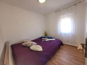 a bedroom with a purple bed with pillows and a window at Ferienwohnung Istrien 200m Strand in Fažana +50 photos