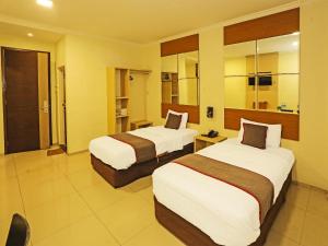ein Hotelzimmer mit zwei Betten in einem Zimmer in der Unterkunft Super OYO Townhouse OAK Hotel Fiducia Serpong in Serpong