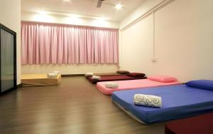 a room with three beds in it with pink curtains at Hotel O The Space Inn in Kuala Terengganu