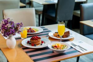 a table with plates of breakfast food and orange juice at HF Ipanema Park in Porto