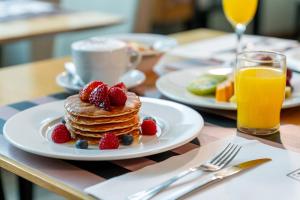a plate of pancakes with strawberries and fruit on a table at HF Ipanema Park in Porto