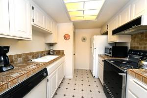 a kitchen with white cabinets and a white refrigerator at Plaza Villas Getaway - 1br Downtown PS in Palm Springs