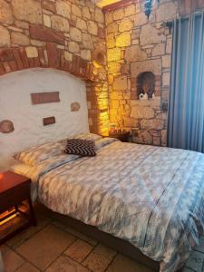 a bedroom with a large bed with a stone wall at KEYİFTE Alaçatı in Alacati