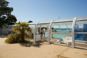 a glass building with a pool and people in it at Camping Au Soir D'été in Mesquer