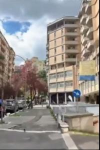 een stadsstraat met een hoog gebouw op de achtergrond bij Appartamento Trastevere & Pascarella in Rome