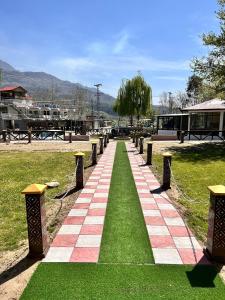 Jharoka Resort - Taranna, Balakot في Hassa: ممشى في حديقة بها عشب وكراسي