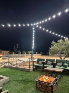 een patio met banken en 's nachts een vuurplaats bij منتجع ومزرعة برزان in Ad Diḩwah
