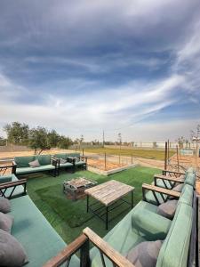 een patio met banken en tafels en een veld bij منتجع ومزرعة برزان in Ad Diḩwah
