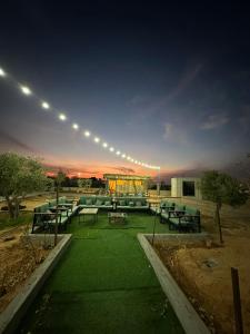 een groep tafels en stoelen in een park 's nachts bij منتجع ومزرعة برزان in Ad Diḩwah
