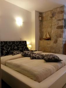 a large bed in a bedroom with a stone wall at Studio Kairos in Trogir