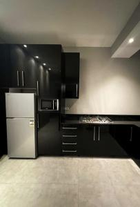 a kitchen with black cabinets and a refrigerator at Nicole 2BR in Gemmayze in Ar Rumayl +6 photos
