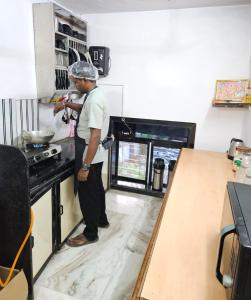 un hombre de pie en una cocina preparando comida en Astha Kandivali Service Apartment, en Bombay