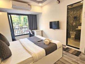 Un dormitorio con una cama y un televisor y una ventana. en Astha Kandivali Service Apartment, en Bombay