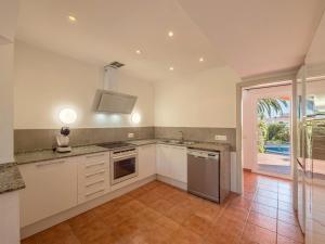 Una cocina con gabinetes blancos y una ventana grande. en Villa Olivia, en Punta Prima