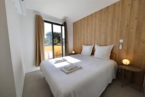 Un dormitorio con una gran cama blanca con ventana. en La Parenthèse Corse - T2 cabine vue mer, en Pianottoli-Caldarello
