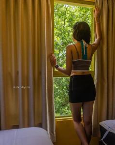 a woman is standing in front of a window at Dumbara Breeze in Hunnasgiriya