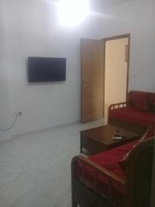 a living room with a red couch and a tv at maison à louer à la grotte de bizerte foret et mer in Banzart