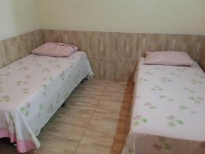 two twin beds in a room with wooden floors at Condominio Nina2 in Icapuí