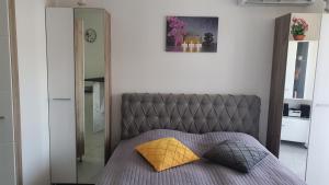 een slaapkamer met een grijs bed met een geel kussen bij Aida in Veliko Gradište