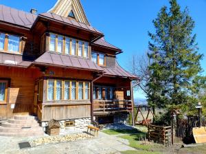 a large wooden house with a tree in front of it at Halne Izby - Pokoje Gościnne in Ząb
