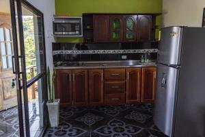 a kitchen with wooden cabinets and a stainless steel refrigerator at EDYMA Cabaña con JACUZZI in Guatapé