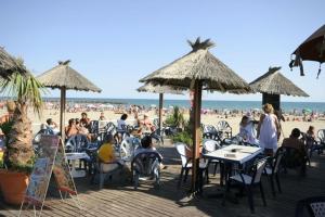 a group of people sitting at tables on the beach at Camping Sable d'Or 3 chambres in Cap d'Agde