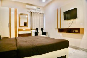 a bedroom with a bed and a desk and a television at Virksham Hotel in Coimbatore