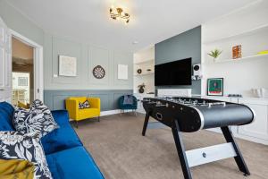 a living room with a blue couch and a tv at LONG TERM STAY SPECIAL OFFER AVAILABLE! 5-Bedroom Spacious, Stunning Design, Sociable Areas & Cosy House Near South Downs Park, Sleeps 11 with GAMES Room, PRIVATE PARKING and GARDEN - by Blue Puffin Stays in Waterlooville