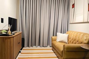 a living room with a couch and a television at Flat centro de Londrina - Vista incrível in Londrina