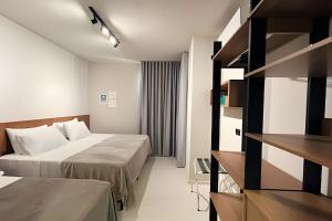 a hotel room with two beds and a book shelf at Flat centro de Londrina - Vista incrível in Londrina