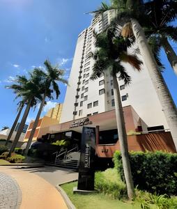 a tall building with palm trees in front of it at Flat centro de Londrina - Vista incrível in Londrina