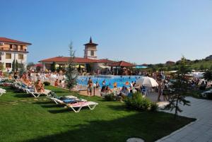 a group of people sitting around a swimming pool at Harmony Hills Tomovi Apartment C12 in Rogachevo
