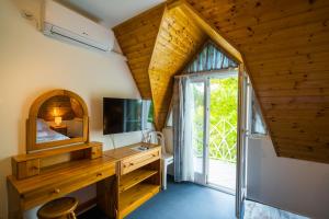 a room with a television and a desk with a mirror at Győrfi Apartmanház Zamárdi in Zamárdi