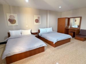 a hotel room with two beds and a mirror at Tokyo Hotel in Nakhon Ratchasima
