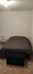 a bed in a white room with a black comforter at F3 plein centre ville de Gien in Gien