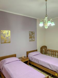 two beds in a room with purple sheets and a chandelier at Casa Lucia in Oppido Mamertina
