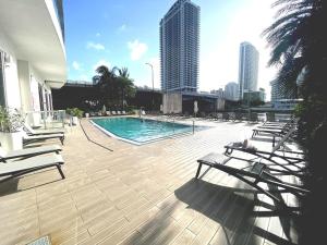 una piscina con bancos y edificios de fondo en Steps from the beach 2B 2B Pool, Gym, and More, en Hallandale Beach