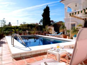 a pool in a yard with a table and chairs at Villa Mara in Caleta De Velez