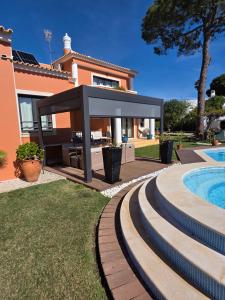 a pavilion in front of a house with a swimming pool at Vila Luz in Vilamoura