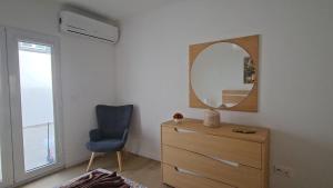 una camera da letto con cassettiera, specchio e sedia di BoaVista House 1 a Maia