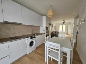 una cucina con mobili bianchi, tavolo e sedie di BoaVista House 1 a Maia